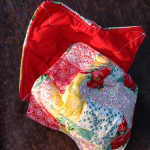 Może przedstawiać: Czerwony, pikowany ochraniacz na miskę z podszewką w kwiatowy wzór. Ochraniacz na miskę jest wykonany z tkaniny i ma pikowany wzór.