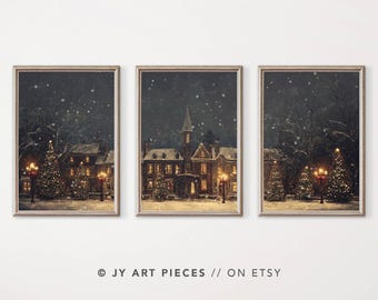 May include: A set of three wintery night scene prints featuring a snow-covered village with a large house, lit up with warm lights, and decorated Christmas trees. The prints are framed in a simple, light brown frame.