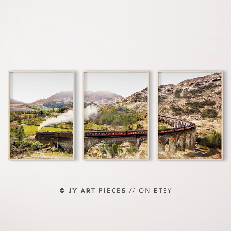 May include: A scenic landscape with a red train traveling over a stone bridge. The train is emitting smoke and is surrounded by green hills and trees. The bridge is made of stone and has many arches. The sky is blue and there are clouds in the distance.