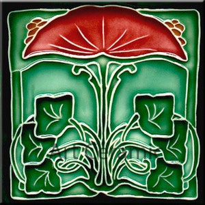 May include: A green and red ceramic tile with a stylised floral design. The tile features a large red flower with a green stem and leaves. The tile is surrounded by a black border.