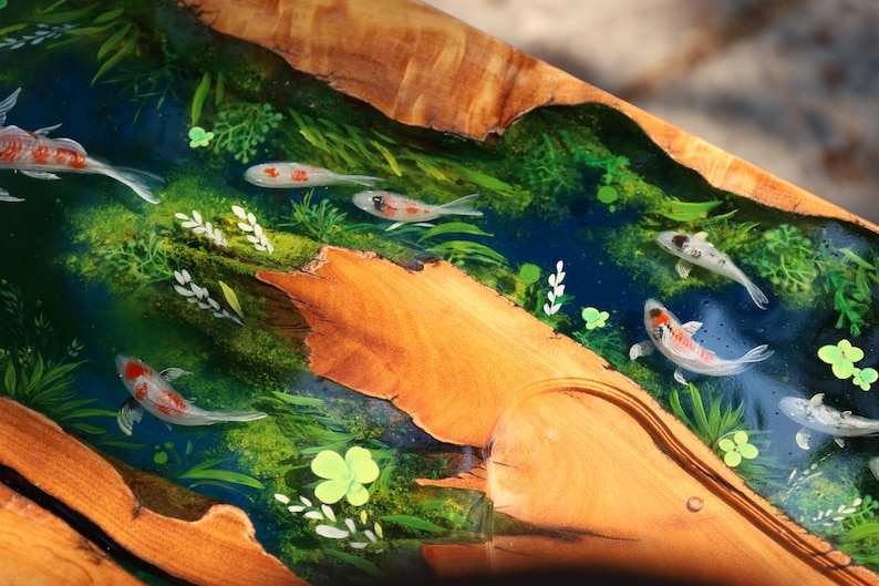 May include: A wooden artwork depicting a river scene with koi carp. The river is painted in blue and green tones, with white, orange, and black koi. The wood has a natural, warm brown colour.