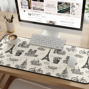 May include: A rectangular desk mouse pad with a black border featuring a cream-colored background and a black and white Parisian theme. The design includes illustrations of the Eiffel Tower, bicycles, and other Parisian landmarks.