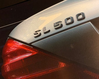 May include: A silver car with a red taillight and the text "SL 500" on the back.