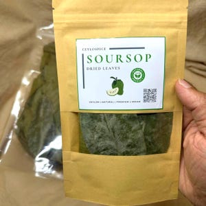 Pode incluir: Uma bolsa bege resselável contendo folhas secas de graviola. O rótulo branco apresenta o texto CEYLOSPICE SOURSOP DRIED LEAVES, uma ilustração de uma graviola verde, um selo de produto 100% natural, um código QR e CEYLON | NATURAL | PREMIUM | VEGAN.