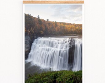 Peut inclure: Une photographie d'une cascade qui se précipite sur des rochers dans un cadre forestier. L'eau coule sur les rochers et crée une brume. Les arbres à l'arrière-plan sont un mélange de vert et de jaune, indiquant le changement de saison.