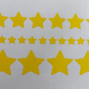 Könnte beinhalten: Ein Blatt mit gelben Papiersternen in verschiedenen Größen. Die Sterne sind in drei Reihen angeordnet, wobei die größten Sterne in der oberen Reihe und die kleinsten Sterne in der unteren Reihe sind.