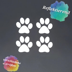 Könnte beinhalten: Vier weiße Pfotenabdruck-Aufkleber in quadratischer Anordnung. In der oberen rechten Ecke befindet sich ein aquarellartiger Fleck mit dem Text Reflektierend, in der unteren linken Ecke ein Fleck mit dem Text verschiedene Größen.