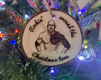 Può includere: Un ornamento natalizio rotondo in legno con un'immagine bruciata di un uomo con un tatuaggio sul braccio. L'ornamento ha il testo "Rockin' around the Christmas tree" scritto su di esso.