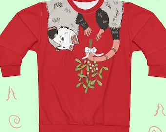 May include: Red sweatshirt featuring a cartoon opossum hanging from mistletoe. The opossum is gray and white with a pink tail. The mistletoe has green leaves and white berries. The sweatshirt has a crew neck and long sleeves.
