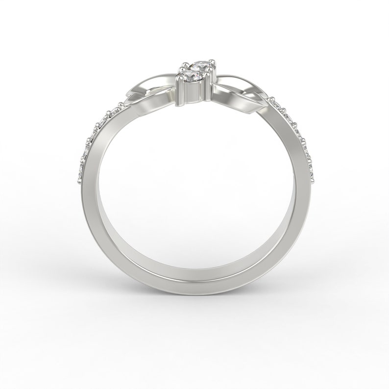 May include: A silver ring with a knot design and small diamonds set in the knot. The ring is on a white background.