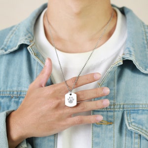 May include: A silver paw print pendant necklace on a silver chain.