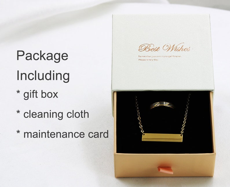 May include: A gold necklace with a bar pendant and a ring inside a white gift box with a gold ribbon. The box has the text "Best Wishes" on the top and "Remember you are my girl forever. Happy every day." inside. The box also includes a cleaning cloth and a maintenance card.