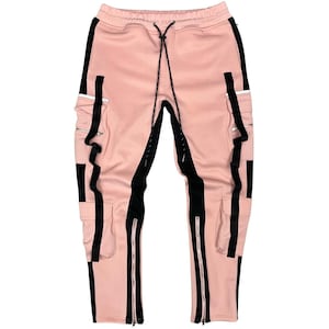 May include: Pink cargo pants with black side stripes and zippers at the ankles. The pants have a drawstring waist and cargo pockets. The design includes reflective accents.