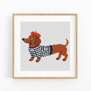May include: A framed print featuring a dachshund wearing a red beret and a black and white striped shirt. The dog is brown with a long body and short legs. The artwork is a cross-stitch style with a light gray background.