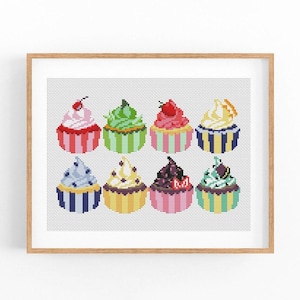 Op de afbeelding: Een ingelijste kruissteek met acht kleurrijke cupcakes. Elke cupcake heeft een uniek glazuurontwerp en zit in een gestreepte vorm. De cupcakes zijn versierd met kersen en andere decoratieve elementen.