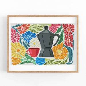 May include: A framed cross-stitch artwork featuring a dark gray coffee maker and a red coffee cup. The design is surrounded by colorful flowers in shades of yellow, orange, pink, blue, and red, with green leaves.