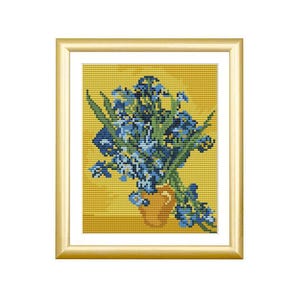 May include: A cross-stitch embroidery of blue irises in a yellow pitcher, set against a vibrant yellow background. The artwork is encased in a simple, polished gold-toned frame with a white mat border, creating a clean and structured presentation.