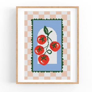 Puede incluir: Una obra de arte en punto de cruz enmarcada que presenta un grupo de tomates rojos con tallos y hojas verdes. Los tomates están colocados sobre un fondo azul claro dentro de un borde verde. El fondo tiene un patrón de cuadros rosas y blancos.