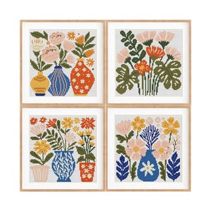 May include: Four framed cross-stitch artworks featuring floral arrangements in vases. The color palette includes pink, yellow, orange, and blue. Each piece is in a wooden frame, creating a cohesive set for home decor.