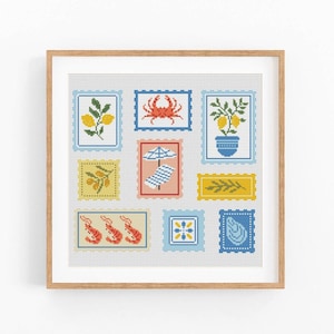 May include: A framed cross-stitch artwork with nine postage stamp designs. The stamps show coastal and Mediterranean themes, including lemons, crabs, shrimp, and beach scenes. The colour palette includes blue, yellow, red, and white.