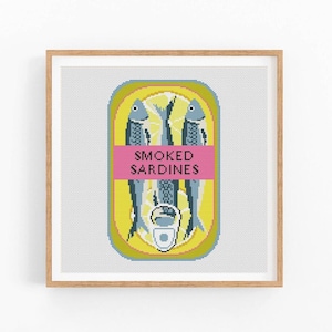 May include: A cross-stitch pattern of a yellow can of smoked sardines with three blue fish inside. The can has a pink label that says "SMOKED SARDINES".