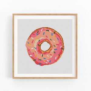 May include: Pink frosted donut with colorful sprinkles. The donut is a cross-stitch pattern.