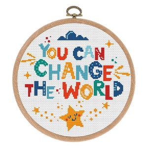 May include: A white embroidery hoop with a colorful cross-stitch design that reads "YOU CAN CHANGE THE WORLD". The design also includes a yellow star with a smiling face and a blue cloud.