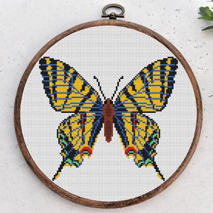 May include: A yellow and blue butterfly cross-stitch pattern in a wooden embroidery hoop.