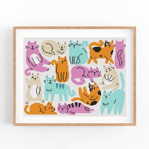 Puede incluir: Una impresión enmarcada con un patrón de gatos estilizados en varias poses. Los gatos son de color rosa, naranja, azul y beige, con contornos negros. La obra de arte se muestra en un marco de madera marrón claro.