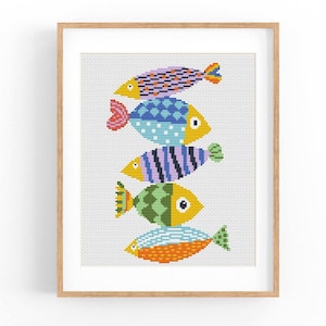 May include: A cross-stitch pattern featuring five colorful fish stacked on top of each other. The fish are in shades of blue, green, yellow, orange, and purple.