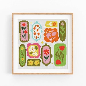 May include: A framed floral art print featuring a collection of colorful, stylized flower designs. The artwork showcases various shapes and sizes, with a palette of pink, orange, green, and yellow. The print is set against a white background.