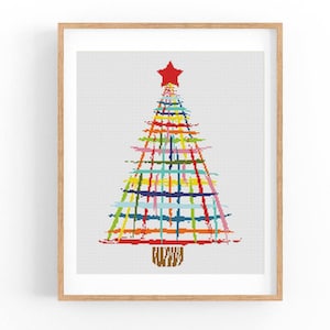 Puede incluir: Un árbol de Navidad abstracto colorido con una estrella roja en la parte superior. El árbol está formado por una serie de líneas horizontales de varios colores, incluidos el rojo, el naranja, el amarillo, el verde, el azul y el morado. El árbol está enmarcado en un marco de madera claro.