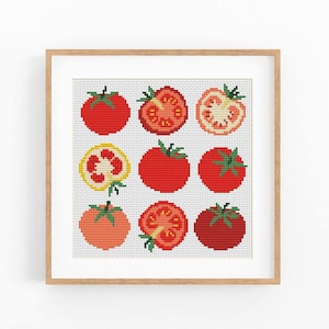 May include: A framed cross-stitch pattern featuring a grid of nine tomatoes in various states of ripeness and cross-sections. The design includes whole red tomatoes, sliced tomatoes showing seeds and pulp, and a yellow tomato slice, all in a light wood frame.