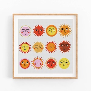 Peut inclure: Une œuvre d'art encadrée présentant une grille de douze illustrations de soleil stylisées. Chaque soleil a une expression et une palette de couleurs uniques, comprenant des nuances de jaune, d'orange, de rouge et de rose. L'œuvre est sur fond gris clair.