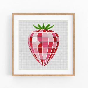 Pode incluir: Uma obra de arte em ponto cruz emoldurada com um design geométrico de morango. O morango é renderizado em tons de vermelho e rosa, com um caule verde. A obra de arte é definida contra um fundo branco.