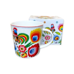 May include: White ceramic mug with a colorful Polish folk art design featuring roosters and flowers. The mug comes in a matching box.