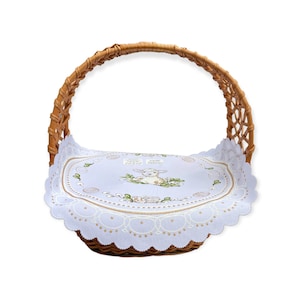 May include: A wicker basket with a white and blue embroidered liner featuring a lamb and the text "Jajeczko Pierwsze".