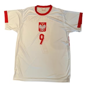 May include: White soccer jersey with red trim on the collar and sleeves. The jersey features the Polish coat of arms and the number 9 in red. The word "POLSKA" is above the coat of arms.