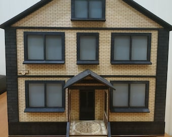 May include: A model of a two-story house with a brick facade, black trim, and a small porch with steps. The house has six windows, all with black frames. The windows are all closed.
