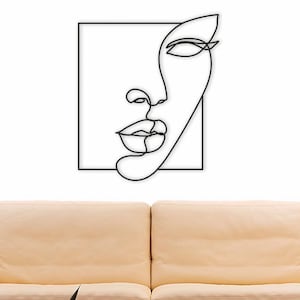 May include: Black and white line art wall decor of a face with a square frame. The face is drawn in a single line.