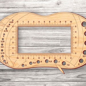 May include: A wooden knitting gauge with a ruler, needle holders, and a circular gauge for measuring knitting needle sizes. The gauge is marked with numbers from 0 to 10 and needle sizes from 2.25 to 4.5.