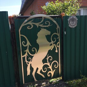May include: A green metal gate with a cut-out design of a horse and vines. The gate is closed and there is a sign that says "ОСТОРОЖНО ЗЛЫЕ СОБАКИ" which translates to "Beware of Vicious Dogs" in English.