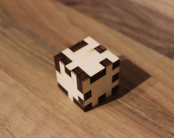 May include: A wooden cube with a geometric pattern. The cube is made of two different shades of wood, creating a contrasting design.