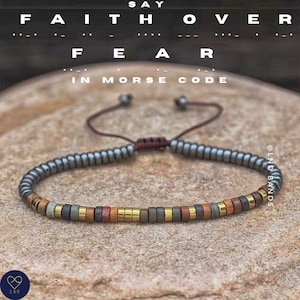 May include: A bracelet with beads spelling "FAITH OVER FEAR" in Morse code. The bracelet has grey, gold, red, and brown beads. The image also shows the words "SAY" and "IN MORSE CODE".