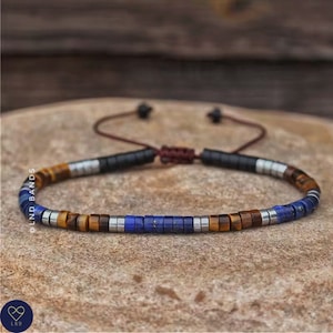 May include: A beaded bracelet with brown, blue and silver beads. The bracelet has a sliding knot closure.