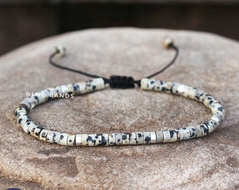 May include: A black and white dalmatian jasper beaded bracelet with silver accents and a black adjustable cord.