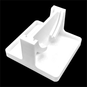 Pu&ograve; includere: Supporto in plastica bianca con una piattaforma rialzata e un supporto curvo. Il supporto &egrave; progettato per contenere un piccolo oggetto, come un telefono o un orologio.