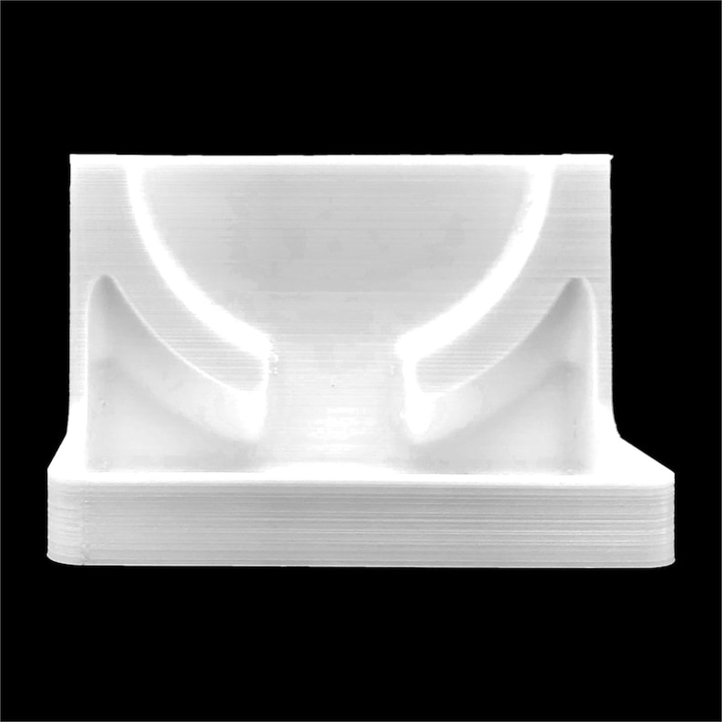 Pu&ograve; includere: Stampo in plastica bianca per la realizzazione di un oggetto stampato in 3D. Lo stampo ha la forma di una tazza con un fondo arrotondato e due manici.