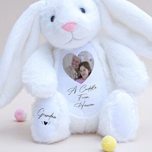 May include: White plush bunny with long ears, a heart-shaped window on its chest with a photo of two people, and the text "A Cuddle From Heaven" and "Grandpa" on the paws.