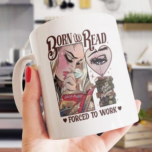 May include: White ceramic mug with a brown graphic of a woman reading a book with the text "Born to Read Forced to Work" and a stack of books with the text "Pages Over Paychecks".